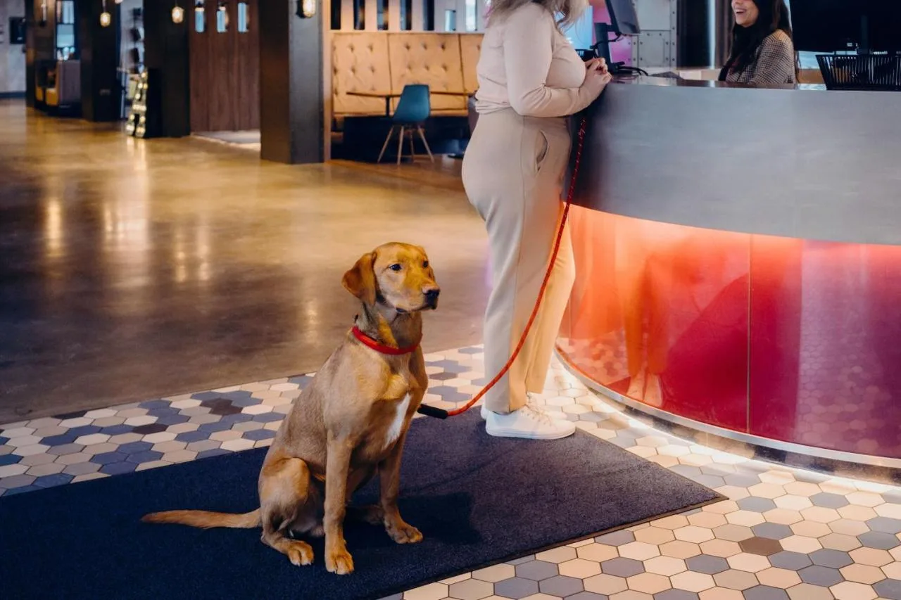 a woman standing next to a dog on a leash at Aloft by Marriott Aberdeen TECA in Aberdeen